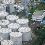 An aerial view shows workers wearing protective suits and masks working atop contaminated water storage tanks at TEPCO's tsunami-crippled Fukushima Daiichi nuclear power plant in Fukushima